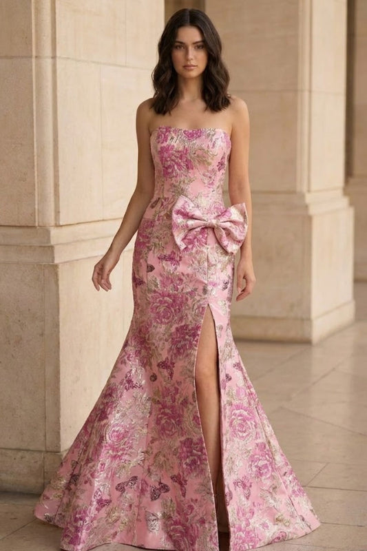 Woman wearing a pink floral evening gown with a large bow in front of classical architecture.